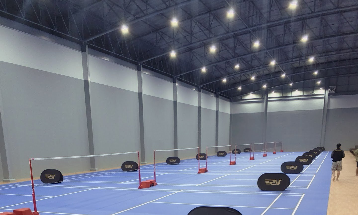 ภายในสนามแบดมินตัน MEOW MINTON พื้นคอร์ตสีน้ำเงิน ใต้หลังคาโครงเหล็กช่วงกว้าง